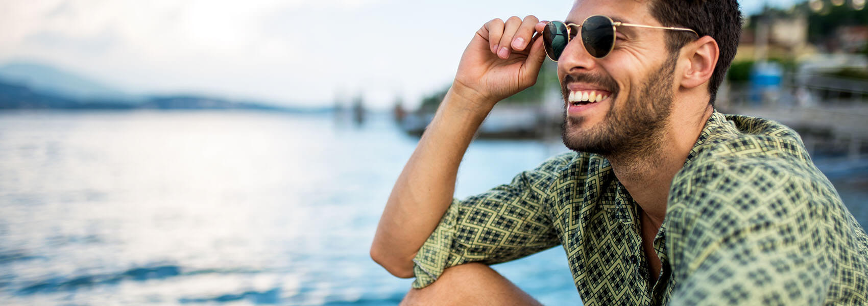 smiling man sitting near a body of water